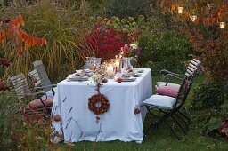 Gedeckter Tisch vor Herbstbeet mit Miscanthus (Chinaschilf) abends