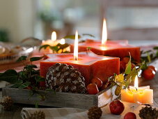 Red star candles with cones, ornamental apples and hedera