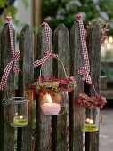 Preserving jars hung on fence as lanterns, small wreaths
