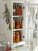 Small cupboard with cooked tomatoes in vinegar, hot peppers and tomato sugo