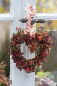 Heart made of roses (rosehip) with moss on the window