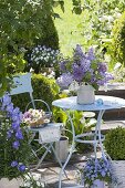 Kleine Terrasse mit blauem Tisch und Stuhl, Strauss aus Syringa (Flieder)