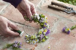 Making a wreath of flowering herbs and strawberries