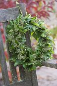 Wreath of hedera with fruit stalks on backrest hanged from bench