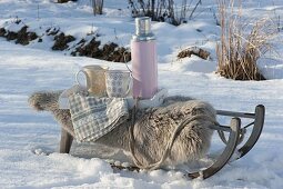 Sled with lambskin and thermos in the snow