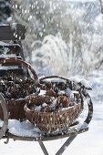 Verschneite Körbe mit verschiedenen Zapfen auf Stuhl