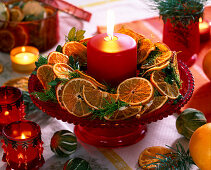 Schale mit Kranz aus Zweigen und Orangenscheiben mit Kerze