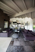 Persian rug in shades of grey and purple sofa set in open-plan interior with white-painted wooden ceiling