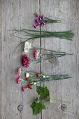 Pinks, grasses, carnations, spray carnations and raspberry leaves on wooden surface