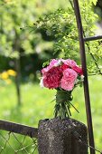 Bouquet of carnations tied with grasses on stone pillar