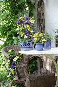 Arrangement of purple and yellow flowers on garden table and wicker armchair