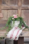 Arrangement of roses and ivy tendrils on rustic wooden table