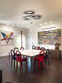 Velvet chairs around table in front of sideboard and modern artwork