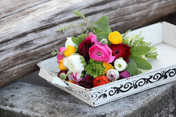 Bouquet of colourful ranunculus on vintage tray