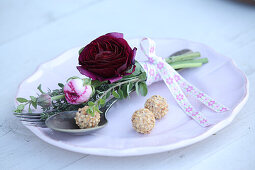 Posy with deep red ranunculus tied to vintage cutlery