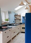 Landhausküche mit schwarzer Küchenarbeitsplatte, weißer Porzellanspüle und blauen Farbakzenten