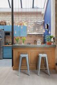 Metal stools at kitchen counter below pendant lamps forming partition