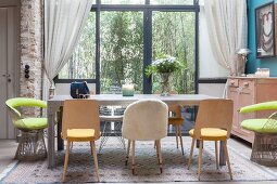 Various chairs around dining table in front of glass wall looking into garden
