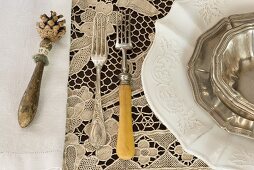 Vintage place setting with silver forks on lace tablecloth