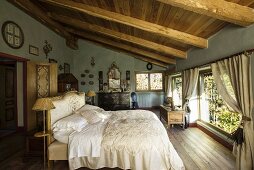 Antique furniture and elegant, vintage-style bed linen in country-style attic bedroom