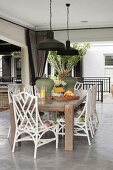 Wooden table and white chairs on veranda with concrete floor