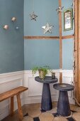 Two side tables in front of blue wall with wainscoting