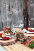 Herbstliche Tischdekoration mit rustikalen Holzscheiben als Tischset und Tellern mit Äpfeln