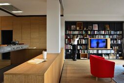 Open-plan living space with modern wooden kitchen and black metal bookcase with integrated TV