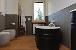 Black, free-standing bathtub against grey wainscoting