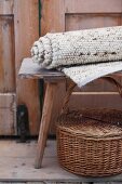 Rolled, hand-woven, undyed woollen rug on wooden stool