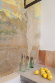 Swing-top bottle and lemons next to wall with layers of old paint