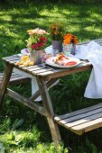 Summery table set for two with colourful posies in garden