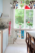 Colourful roller blind on window in vintage-style kitchen-dining room