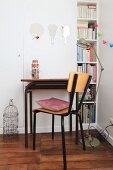 Retro desk and chair in front of white fitted cupboard with bookshelves at one side