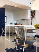 View past dining table into open-plan kitchen with hexagonal floor tiles