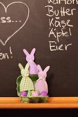 Dyed Easter eggs in egg box and hand-sewn egg cosies against chalkboard wall