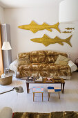 Sofa mit Plaid unter Fischskulpturen, Couchtisch und Coffeetable im Wohnzimmer
