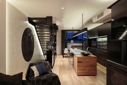 Schwarze Designerküche mit Küchentheke und Essbereich neben Stahltreppe