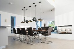 Various black pendant lamps above elegant dining table and chairs in designer apartment