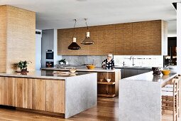 Küchenblöcke mit Holzfronten und Kalkstein-Arbeitsplatte in offener Küche, Frau im Hintergrund