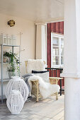 Sheepskin on rattan armchair and lanterns on veranda