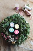 Advent wreath with four colourful candles next to ribbons