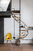 Designer chair next to spiral staircase against white wall