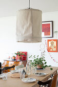 Large ceiling lamp with beige fabric cover above set dining table