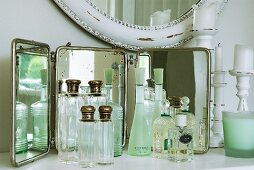 Collection of vintage-style perfume bottles in front of mirror