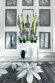 Luxuriant flower arrangement in front of floral artworks on panelled walls