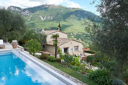 View of pool, stone house and mountain landscape