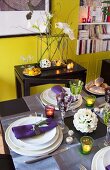 Table festively set with lot tealights in front of white artificial flowers on black console table