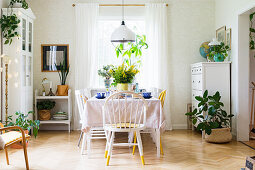 Freundliches Esszimmer mit vielen Zimmerpflanzen und gedecktem Tisch