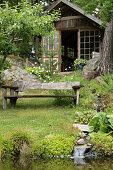 Rustic wooden bench with view of garden pond and orangery in background